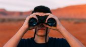 Man looking through binoculars in desert landscape