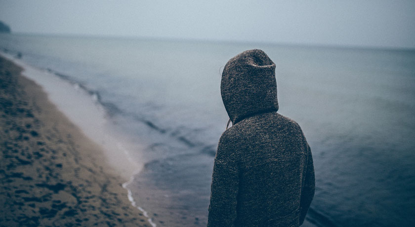 Woman in hoodie walking on beach