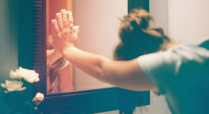 Girl leaning against a mirror