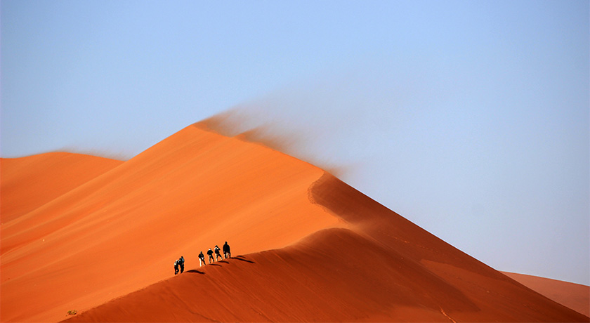 Small group walking on desert sand dunes